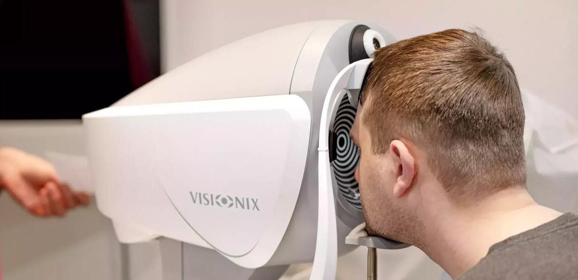Kunde schaut in Wellenfront Gerät, das von Optikerin bedient wird